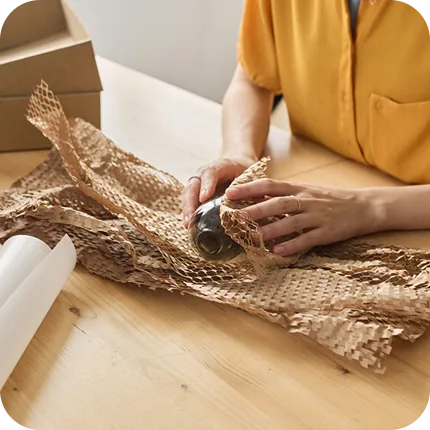 Hands preparing honeycomb kraft wrap for the next order.